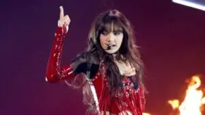 Lisa en concierto de K-pop con vestuario rojo y presentación en vivo sobre escenario con luces intensas